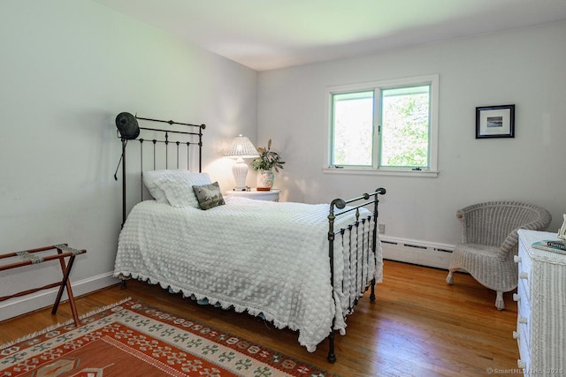 bedroom featuring a baseboard heating unit and wood finished floors
