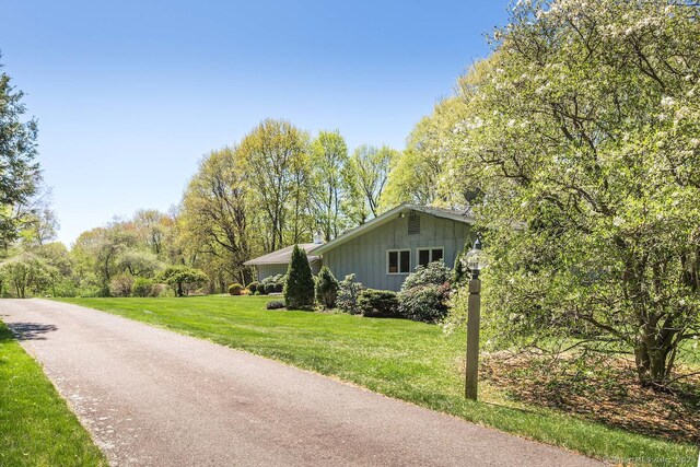 view of side of property with board and batten siding, a yard, and driveway