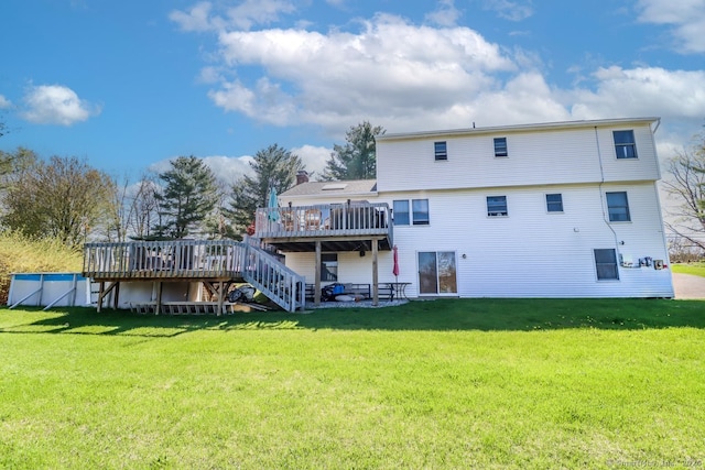 rear view of house with stairway, a deck, and a lawn