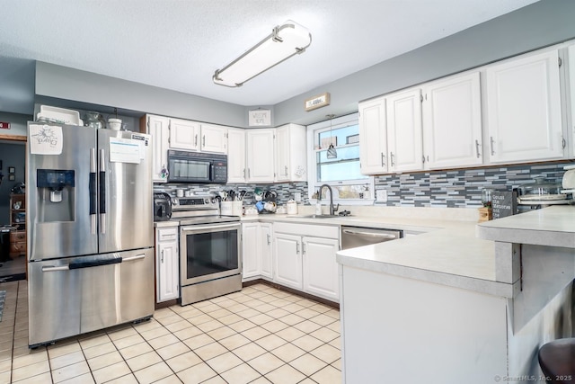 kitchen featuring backsplash, a sink, light countertops, a peninsula, and stainless steel appliances