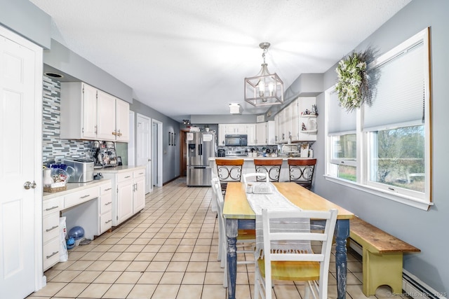 kitchen featuring stainless steel fridge, backsplash, a chandelier, and black microwave