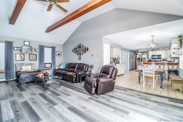 living area with light wood finished floors, ceiling fan with notable chandelier, beam ceiling, and high vaulted ceiling