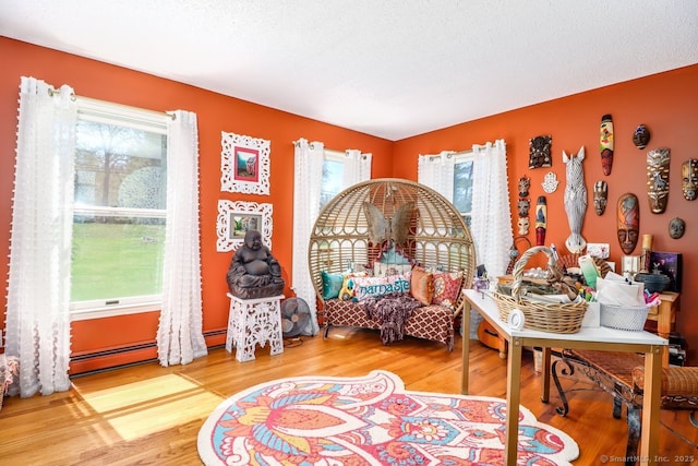 living area featuring a baseboard heating unit and wood finished floors