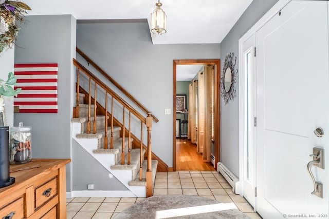 foyer entrance featuring light tile patterned flooring, baseboards, stairway, and a baseboard radiator