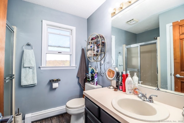 bathroom featuring vanity, wood finished floors, toilet, baseboard heating, and a stall shower
