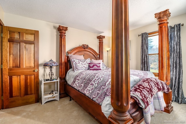 bedroom featuring carpet floors, a textured ceiling, and decorative columns