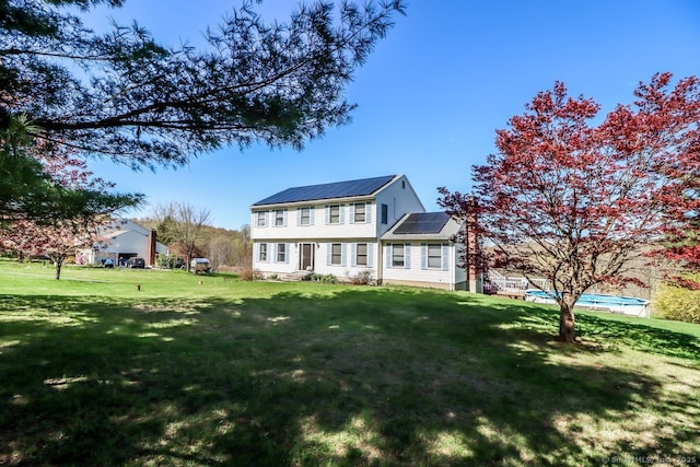 view of front of house with a front yard, entry steps, an outdoor pool, solar panels, and metal roof