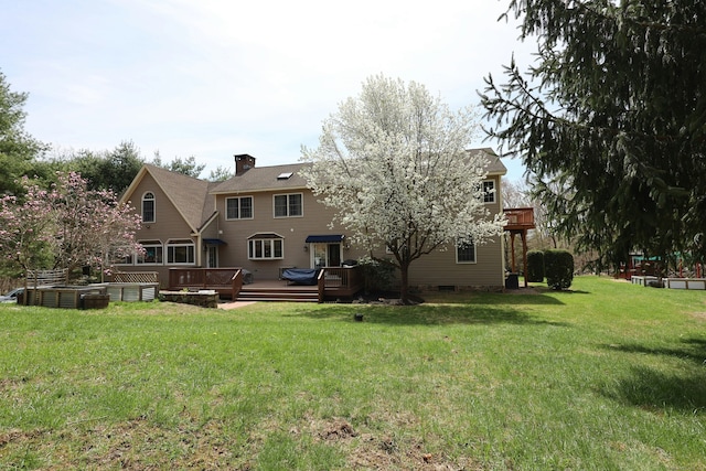 back of house with a lawn, a deck, and a chimney
