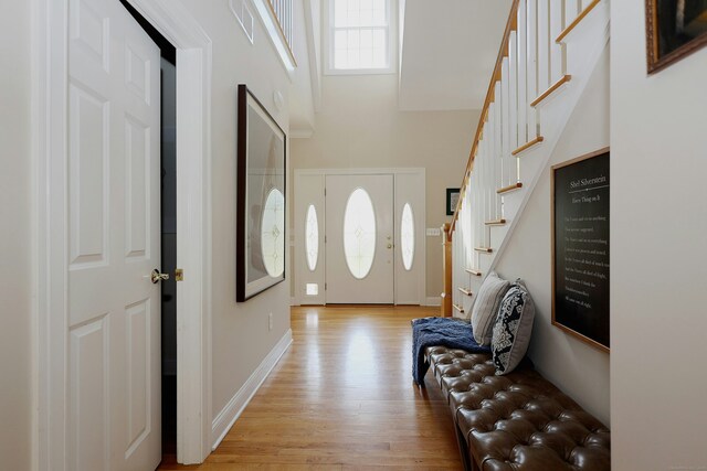 entryway with baseboards, light wood-style flooring, and stairway