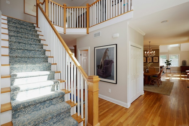 stairs featuring visible vents, baseboards, a notable chandelier, and hardwood / wood-style floors