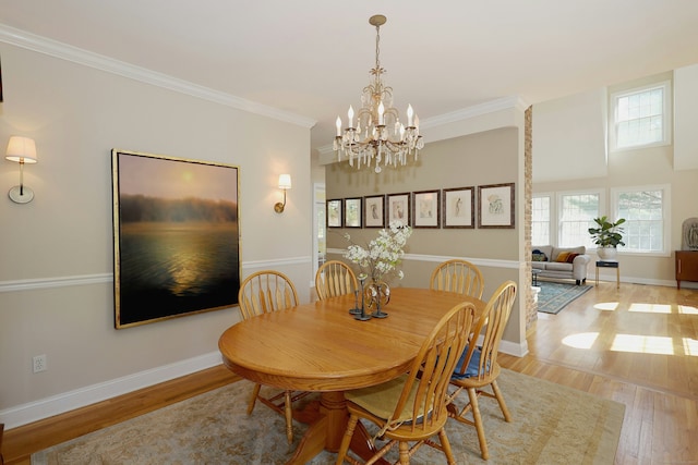 dining area featuring baseboards, ornamental molding, light wood finished floors, and a chandelier