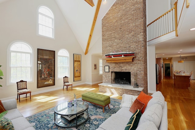 living area with wood-type flooring, high vaulted ceiling, beam ceiling, and a fireplace