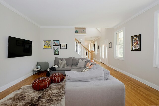 living room with ornamental molding, stairway, and light wood-type flooring