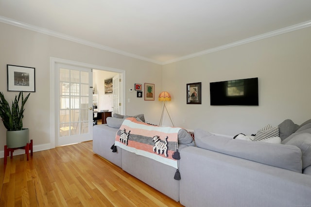 living area featuring crown molding, baseboards, and light wood-style flooring