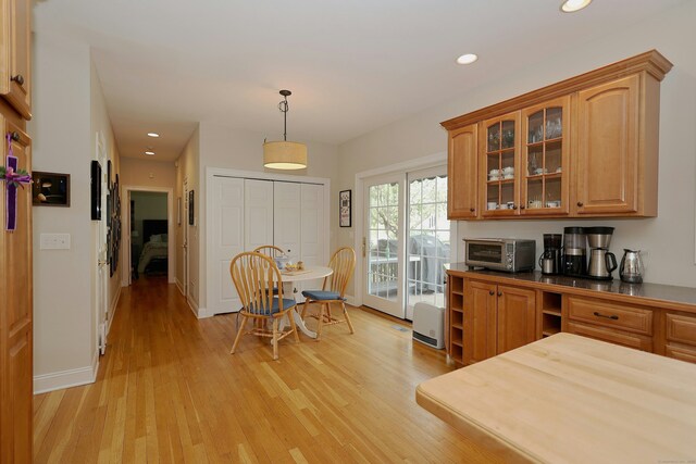 kitchen featuring a toaster, glass insert cabinets, light wood-style floors, recessed lighting, and hanging light fixtures
