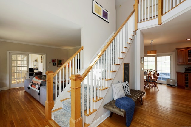 stairs featuring crown molding, baseboards, and wood finished floors