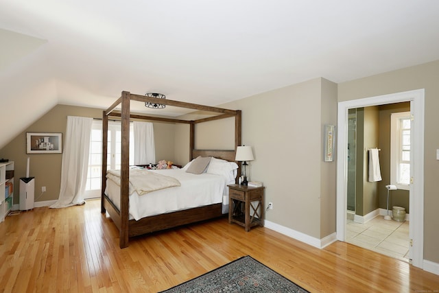 bedroom featuring baseboards, vaulted ceiling, and light wood-style flooring