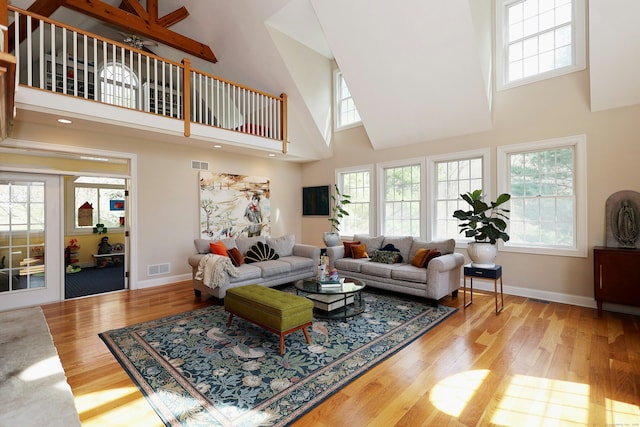 living room featuring a high ceiling, visible vents, and wood finished floors