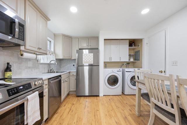 kitchen with appliances with stainless steel finishes, washing machine and clothes dryer, a sink, light countertops, and decorative backsplash