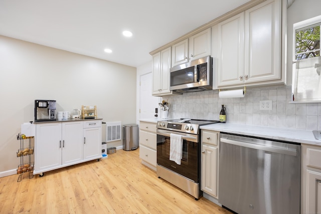 kitchen with appliances with stainless steel finishes, light wood-style floors, decorative backsplash, recessed lighting, and baseboards