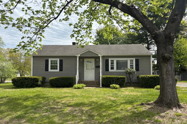 view of front of property with a shingled roof and a front yard
