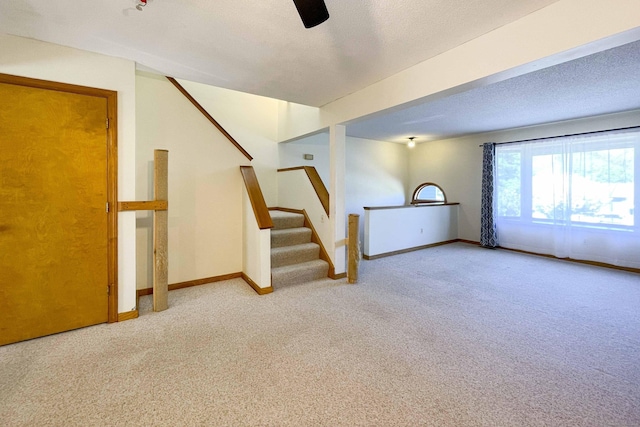 unfurnished living room with stairway, baseboards, carpet, and a ceiling fan