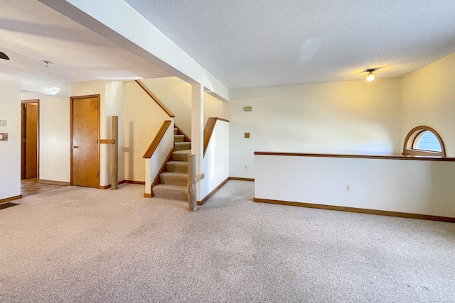 spare room with baseboards, light carpet, stairs, and a textured ceiling