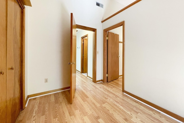 corridor with baseboards, vaulted ceiling, light wood-style flooring, and visible vents