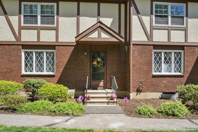 doorway to property with brick siding and stucco siding