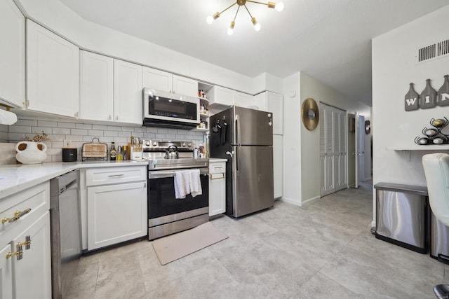 kitchen with stainless steel appliances, an inviting chandelier, decorative backsplash, and white cabinetry