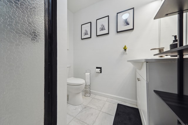 bathroom featuring toilet, baseboards, marble finish floor, and vanity