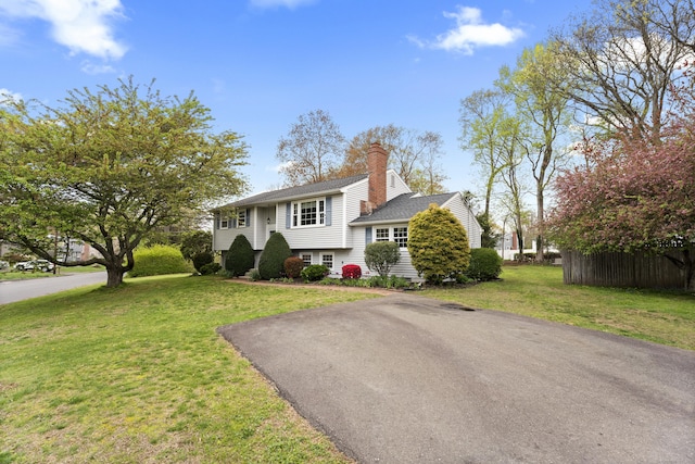 view of front of property with roof with shingles, a chimney, and a front yard