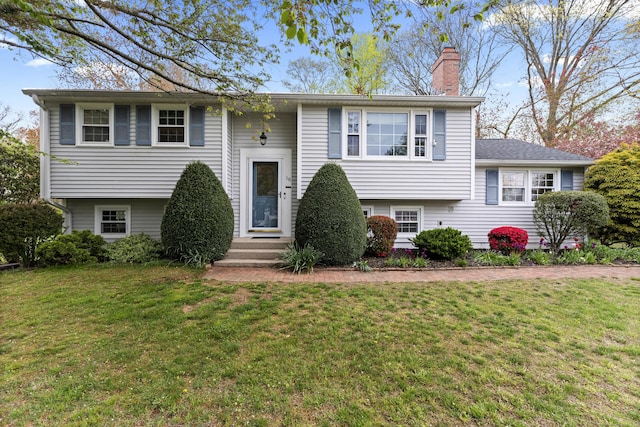 bi-level home featuring a chimney and a front yard