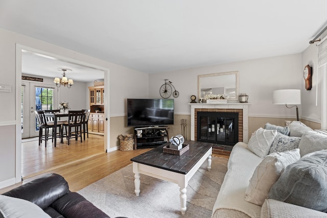 living room with an inviting chandelier, wood finished floors, and a brick fireplace