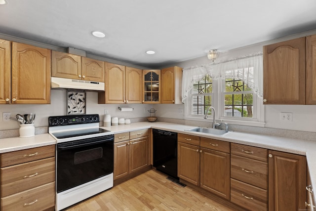 kitchen featuring light wood-style flooring, under cabinet range hood, electric range oven, black dishwasher, and a sink