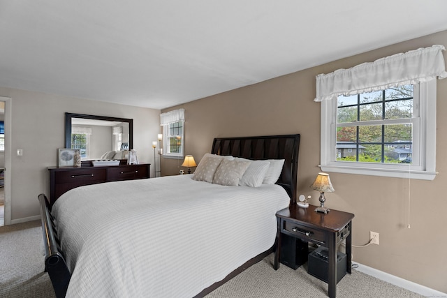 carpeted bedroom featuring multiple windows and baseboards