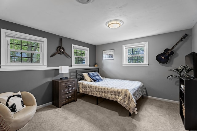 bedroom featuring baseboards, multiple windows, and light carpet