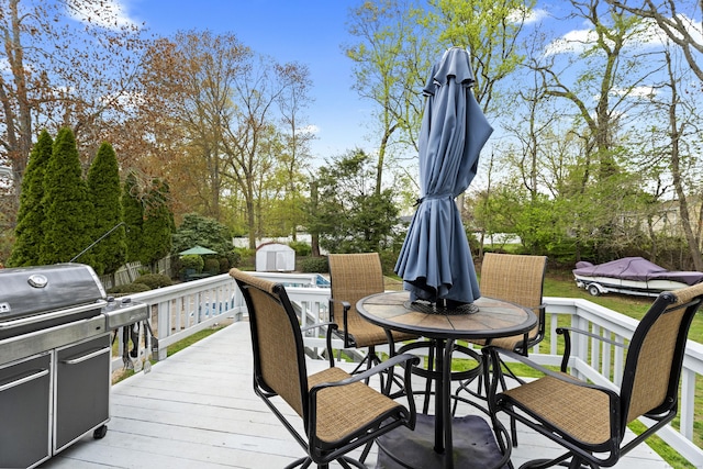 wooden deck with an outdoor structure, outdoor dining area, and a storage unit