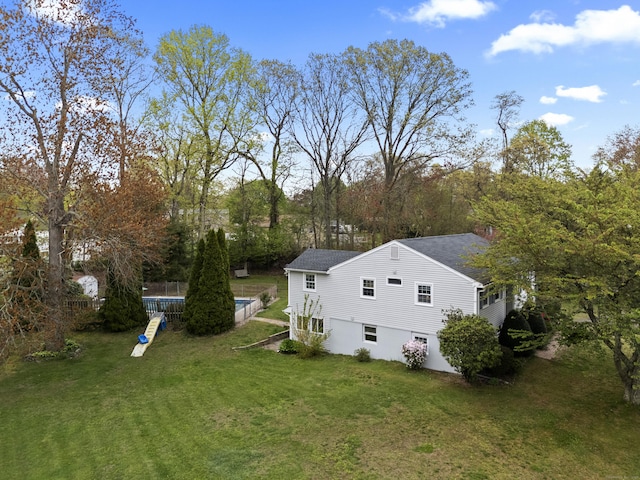 view of home's exterior with a shingled roof, a swimming pool, and a lawn