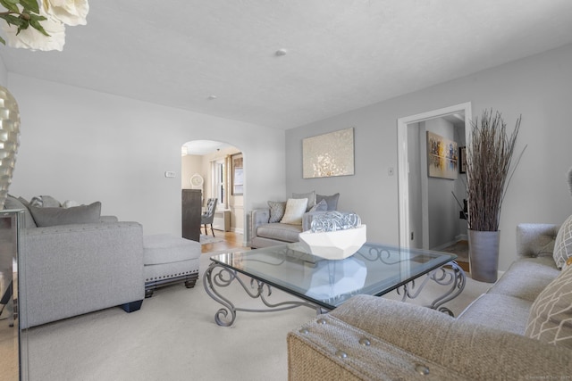 living area featuring arched walkways and carpet