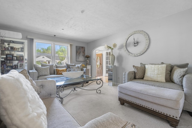 carpeted living room featuring arched walkways and a textured ceiling