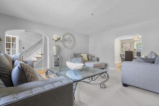 living room with baseboards, arched walkways, and stairway