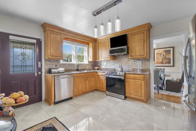 kitchen featuring light stone counters, a sink, decorative backsplash, and stainless steel appliances