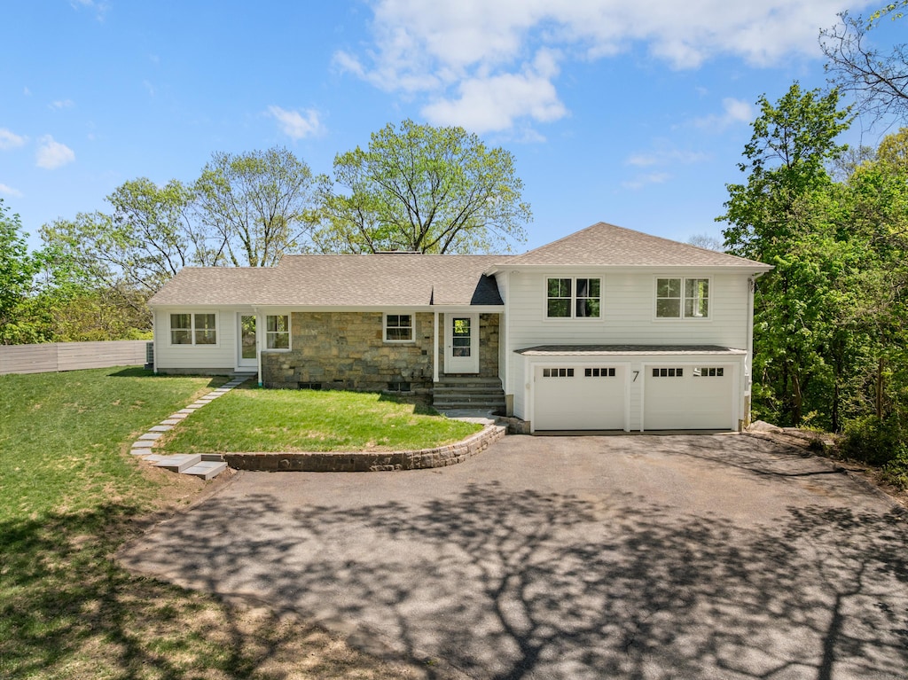 7 Richmond Hill Rd, Norwalk, CT 06854 - tri-level home with a front lawn, fence, stone siding, an attached garage, and driveway