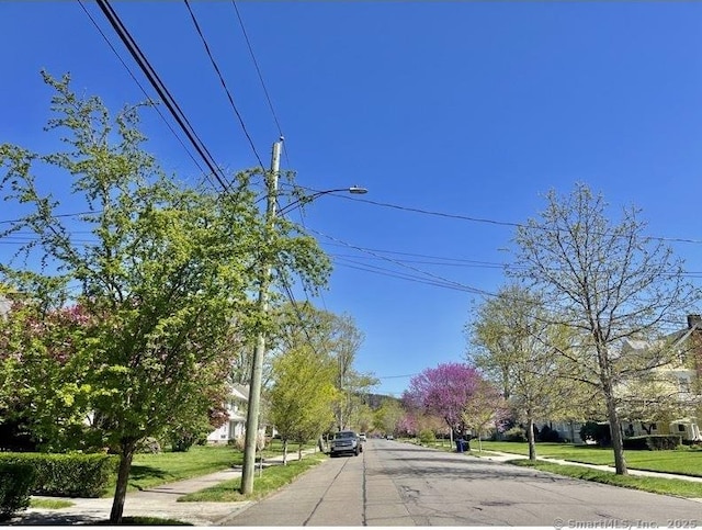 view of road featuring street lighting, sidewalks, and curbs