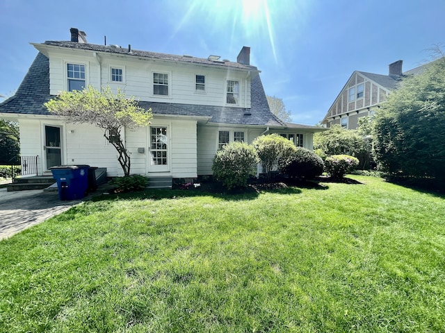 rear view of property with a lawn, a chimney, and entry steps