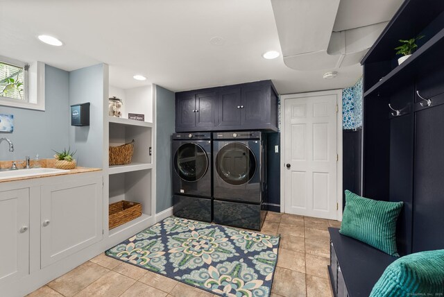 clothes washing area featuring washing machine and dryer, cabinet space, and light tile patterned floors