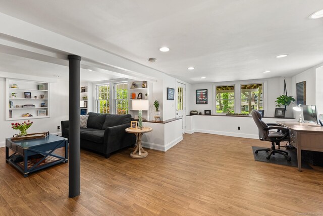 office featuring light wood finished floors, built in shelves, baseboards, and recessed lighting