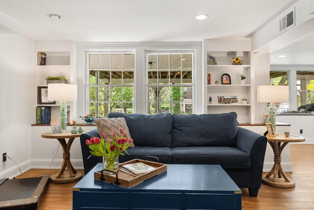 living room featuring wood finished floors, built in features, baseboards, and recessed lighting