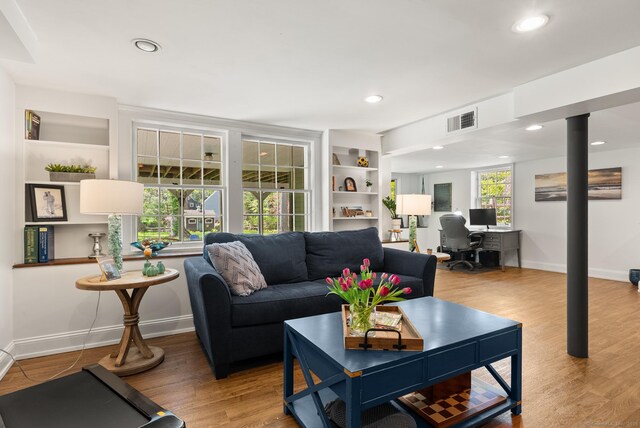 living room featuring a desk, wood finished floors, recessed lighting, baseboards, and built in features